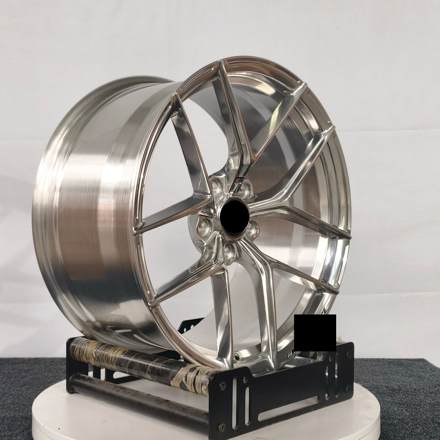 Chrome car wheel on a stand against a white background
