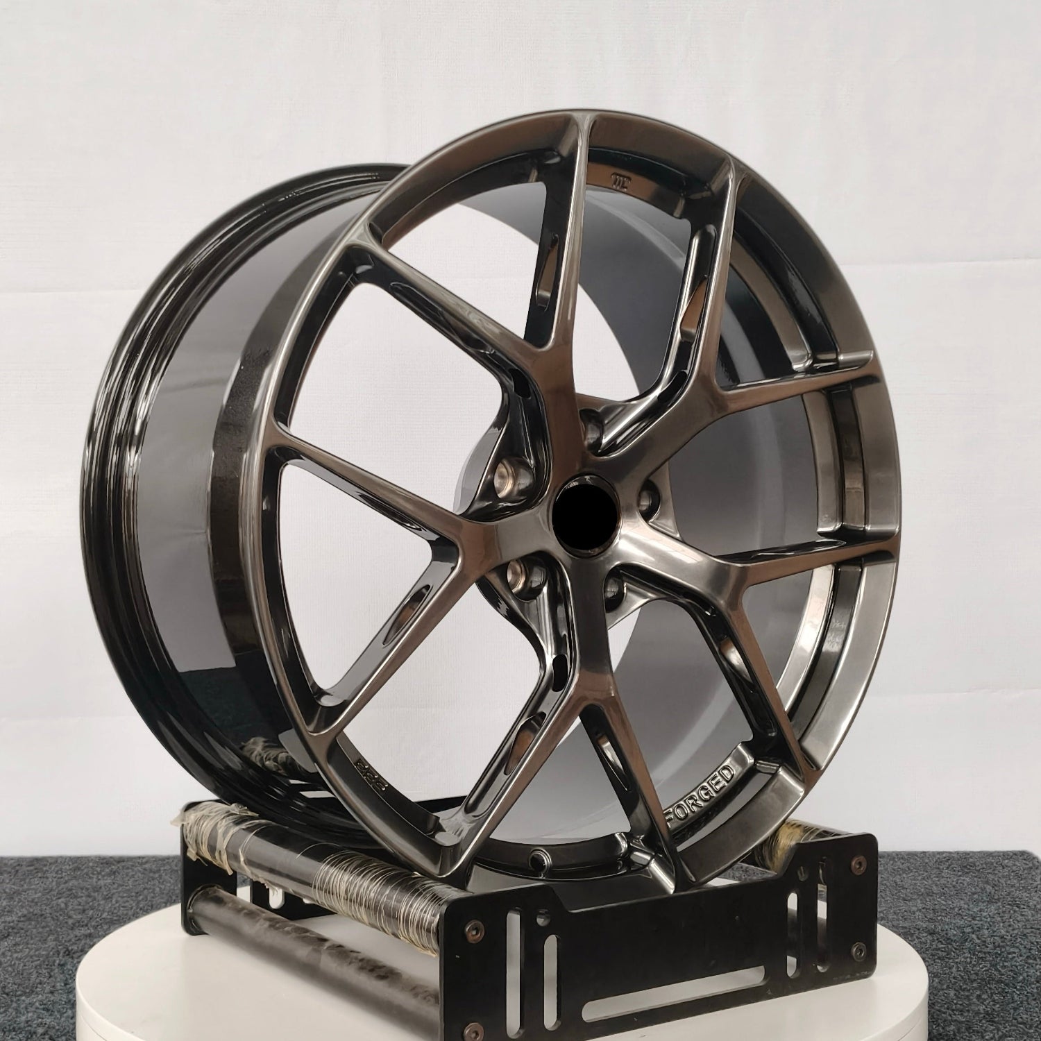Metallic car wheel on a white platform with a gray background