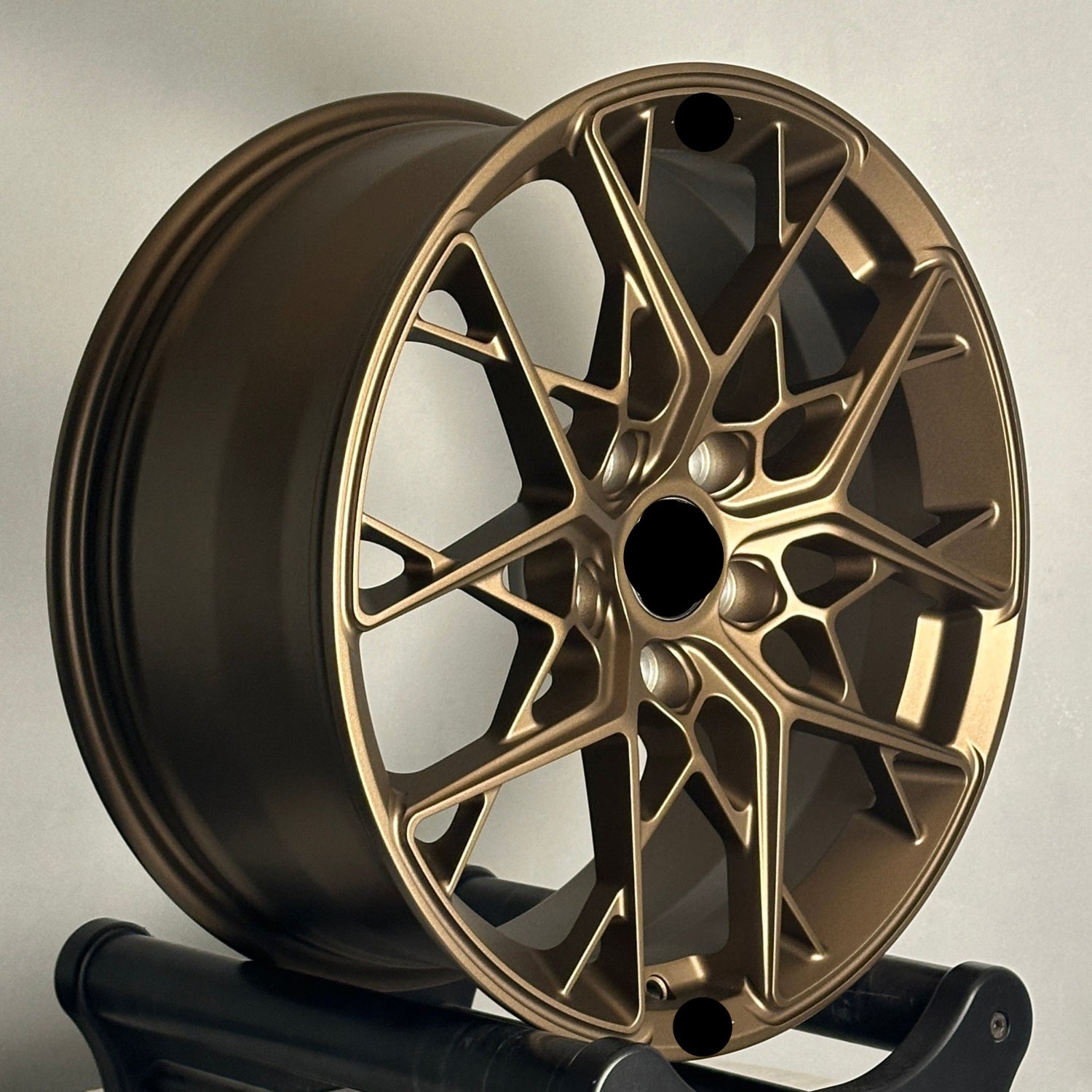 Gold alloy wheel on a stand against a neutral background