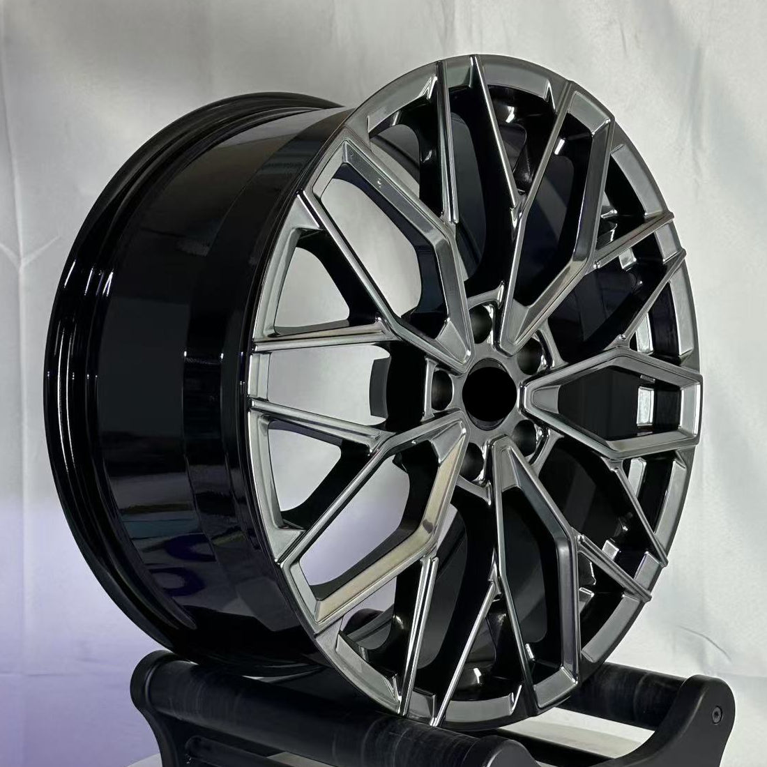 Black alloy wheel on a stand against a white background