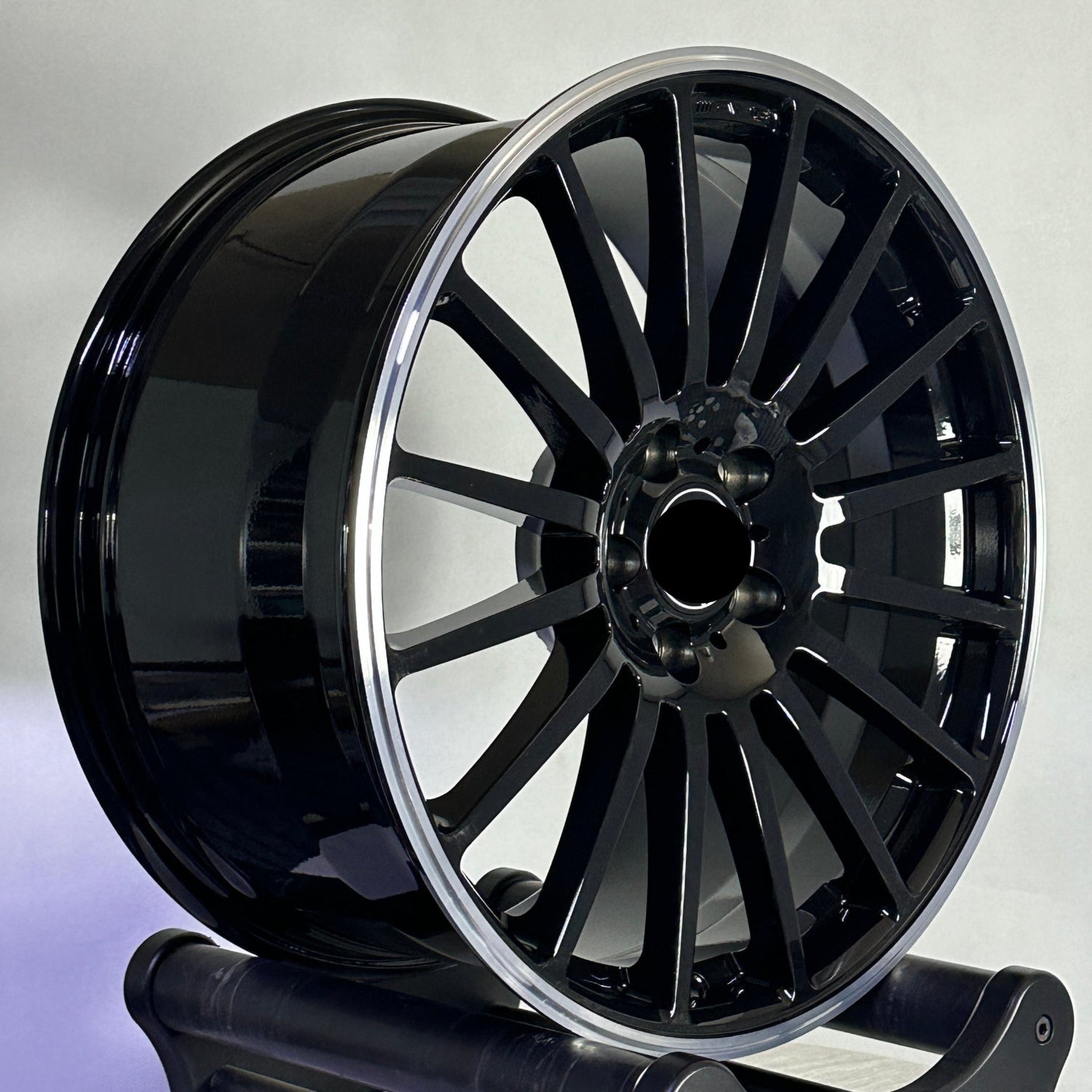 Black Mercedes-Benz car wheel on a stand against a neutral background