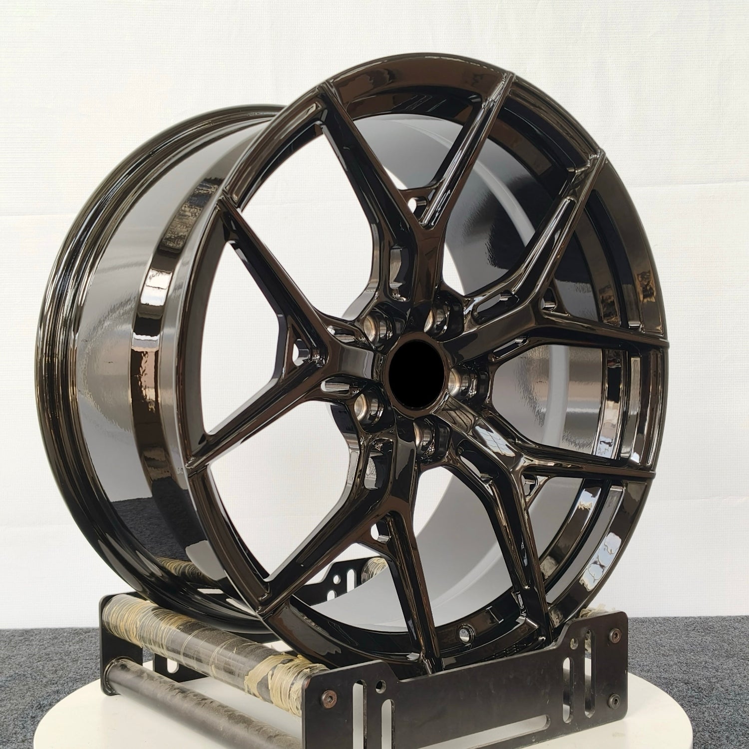 Black alloy wheel on a white stand against a white background