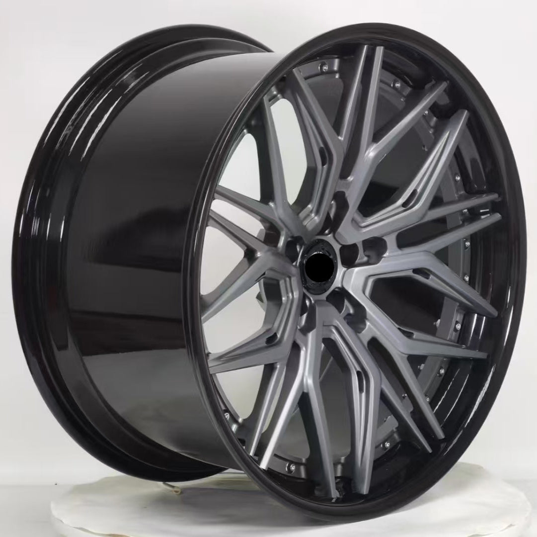 Car wheel rim with black finish and silver accents on a white background
