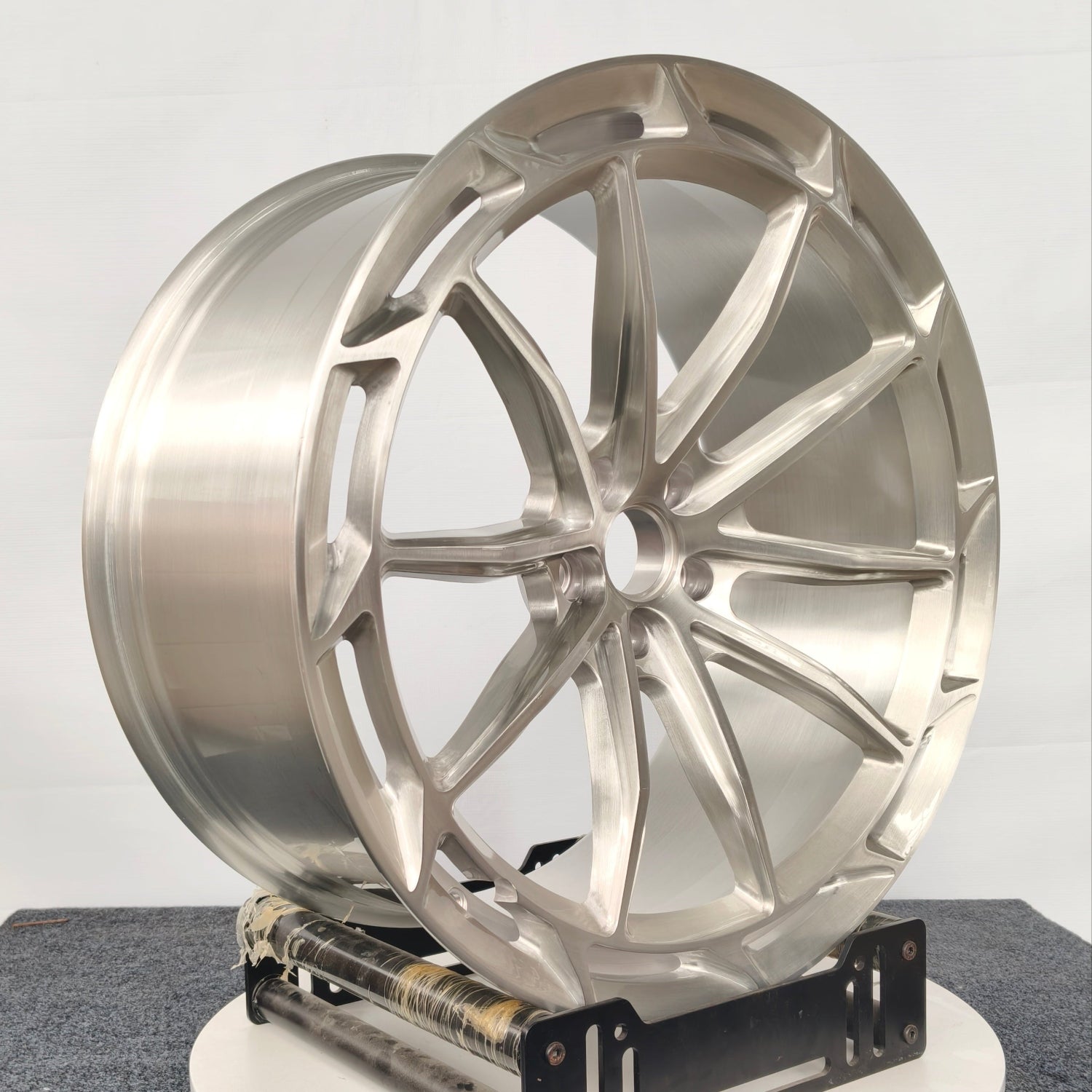 Metallic car wheel on a stand against a white background