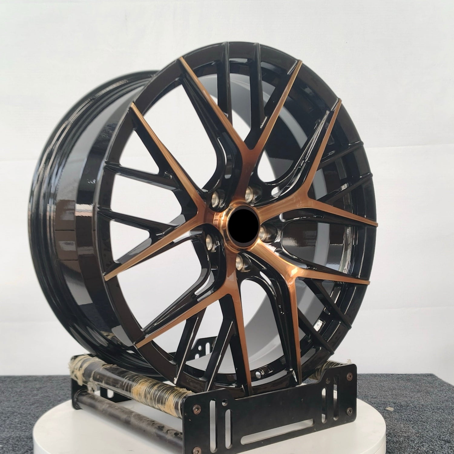 Black and bronze alloy wheel on a white platform with a gray background