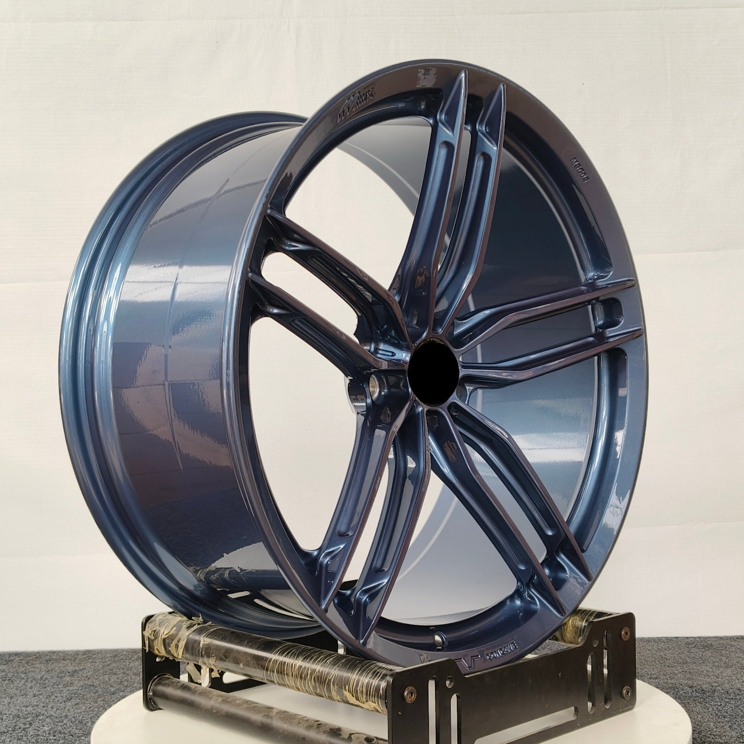 Blue car wheel rim on a white platform against a white background