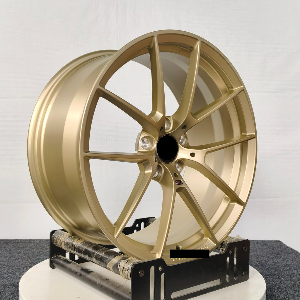 Gold car wheel rim on a white stand against a gray background