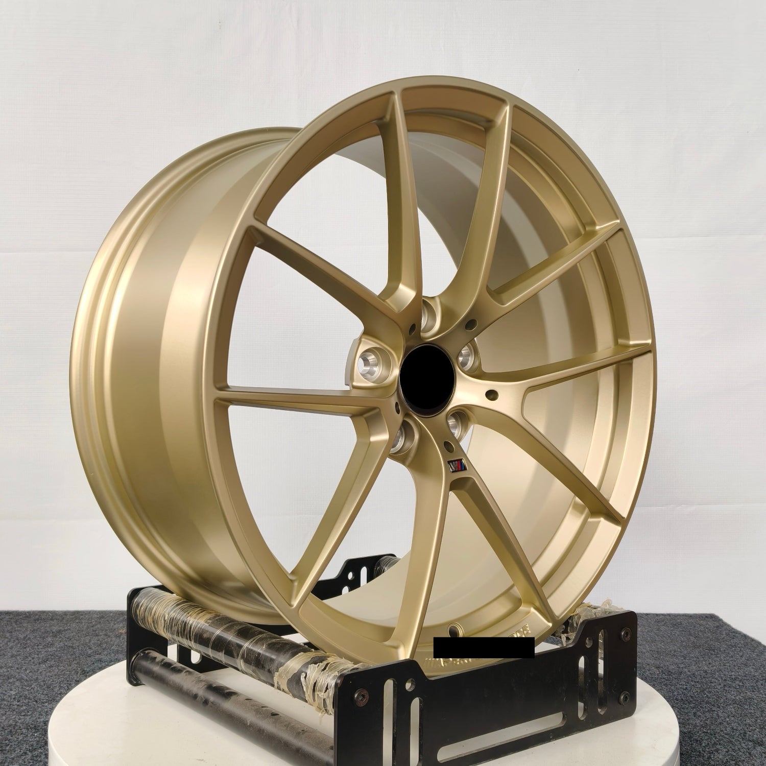 Gold car wheel rim on a white stand against a gray background