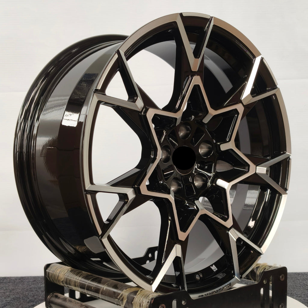 Black BMW alloy wheel on a stand against a white background