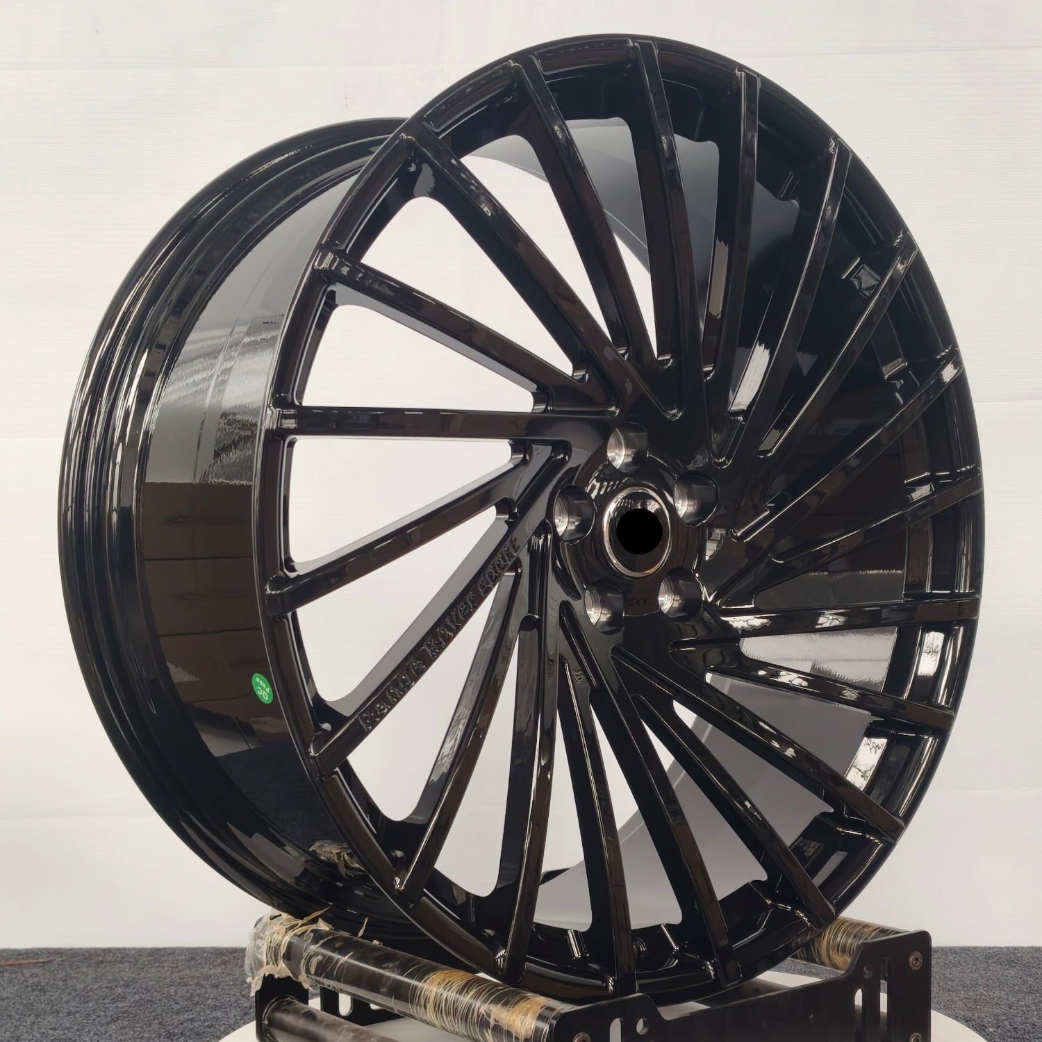 Black alloy wheel on a white platform against a light gray background